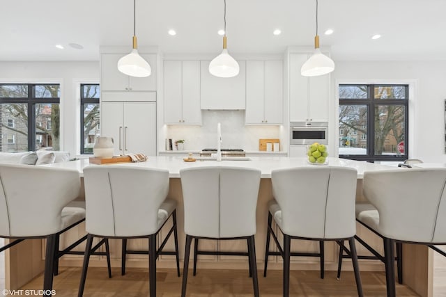 kitchen featuring hanging light fixtures, a breakfast bar area, white cabinets, and appliances with stainless steel finishes