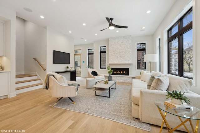 living room featuring ceiling fan, a fireplace, and light hardwood / wood-style floors