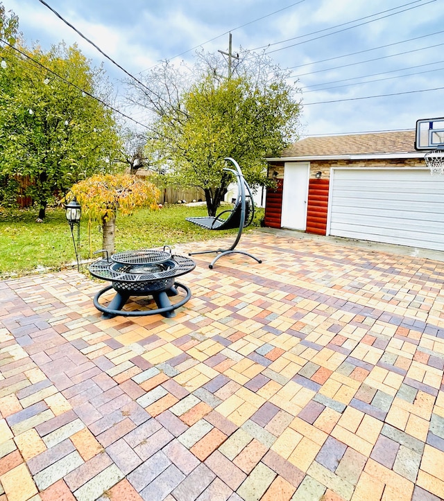 view of patio with a garage, an outdoor structure, and an outdoor fire pit