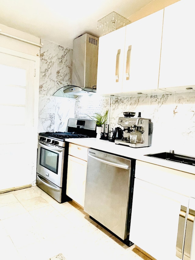 kitchen with backsplash, appliances with stainless steel finishes, ventilation hood, and white cabinets