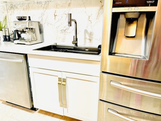 kitchen with appliances with stainless steel finishes, sink, and white cabinets