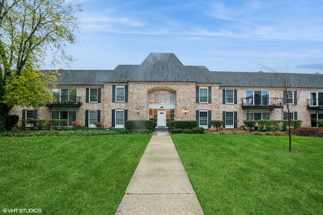 townhome / multi-family property featuring a balcony and a front yard