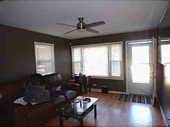 living room featuring wood-type flooring and ceiling fan