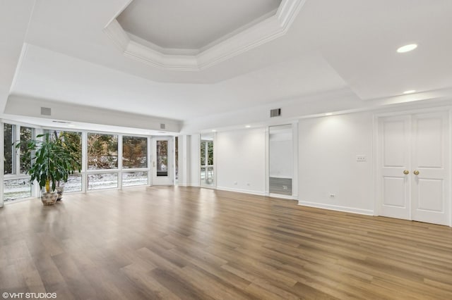 empty room with wood-type flooring, ornamental molding, and a tray ceiling