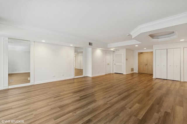 unfurnished living room featuring a tray ceiling, crown molding, and wood-type flooring