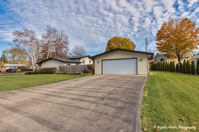 view of front of house featuring a garage, a front lawn, and an outbuilding