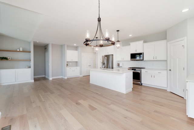 kitchen featuring a kitchen island, white cabinetry, appliances with stainless steel finishes, light wood-type flooring, and pendant lighting