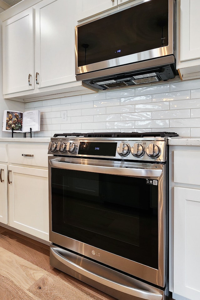 kitchen with white cabinetry, appliances with stainless steel finishes, and light hardwood / wood-style flooring