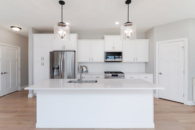 kitchen with white cabinets, stainless steel appliances, and a center island with sink