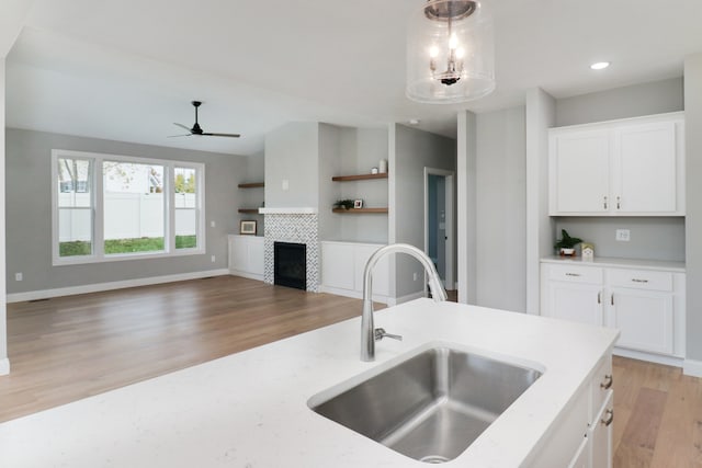 kitchen featuring pendant lighting, sink, light hardwood / wood-style floors, and white cabinets