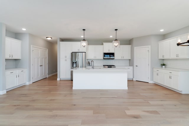 kitchen with white cabinetry, a center island with sink, pendant lighting, and appliances with stainless steel finishes