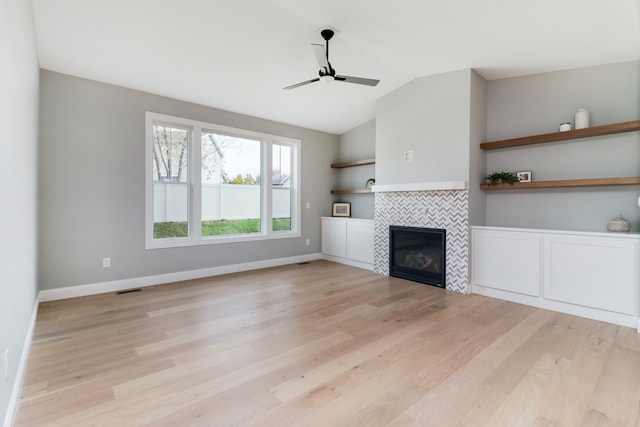 unfurnished living room featuring ceiling fan, vaulted ceiling, light hardwood / wood-style floors, and a fireplace