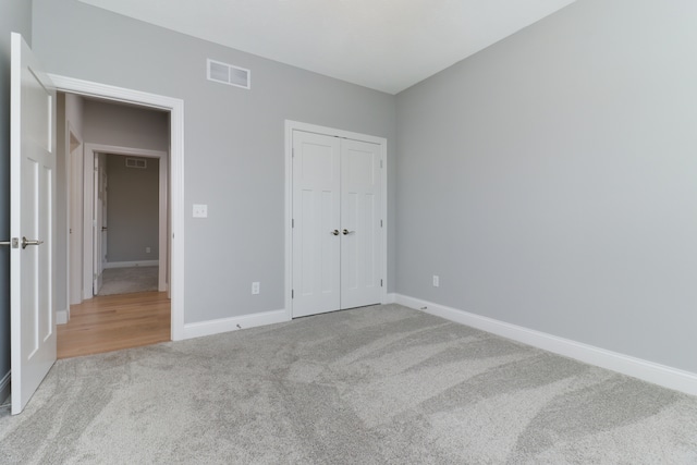 unfurnished bedroom featuring light carpet and a closet