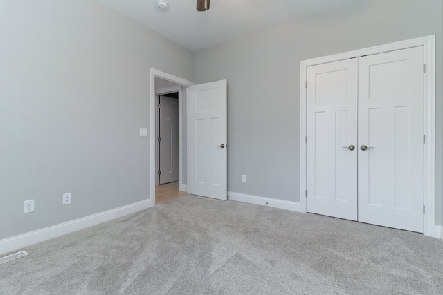 unfurnished bedroom with ceiling fan, light colored carpet, and a closet