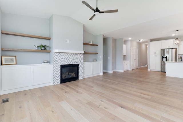 unfurnished living room featuring ceiling fan, lofted ceiling, light hardwood / wood-style floors, and a fireplace