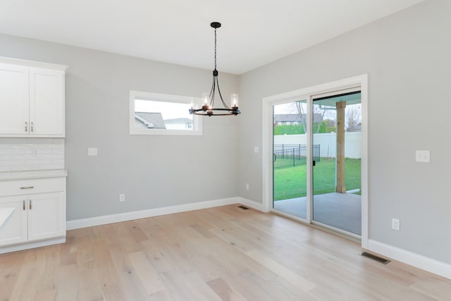 unfurnished dining area with a notable chandelier and light hardwood / wood-style floors