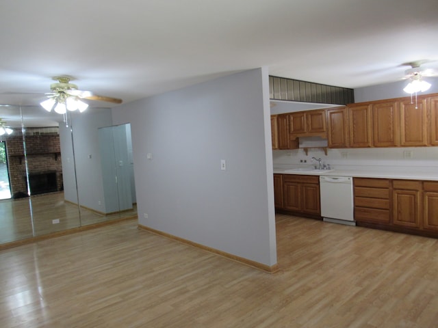 kitchen with a brick fireplace, light hardwood / wood-style floors, white dishwasher, sink, and ceiling fan