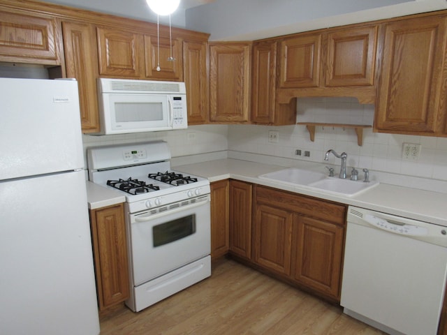 kitchen with white appliances, sink, light wood-type flooring, and tasteful backsplash