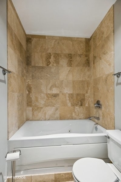 bathroom featuring tiled shower / bath combo and toilet