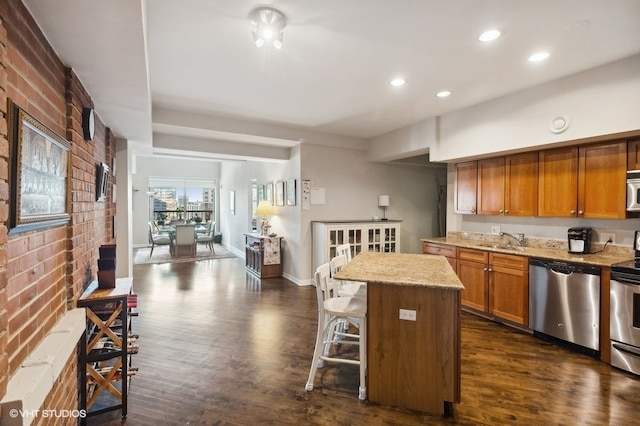 kitchen with a breakfast bar, a kitchen island, dark wood-type flooring, and appliances with stainless steel finishes