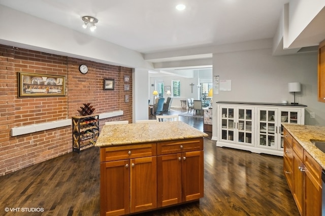 kitchen with light stone countertops, a center island, dishwasher, and dark wood-type flooring