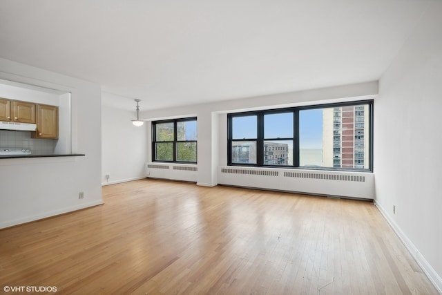 unfurnished living room featuring light wood-type flooring and radiator heating unit