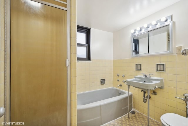 bathroom featuring a bathing tub, tile patterned flooring, tile walls, and toilet