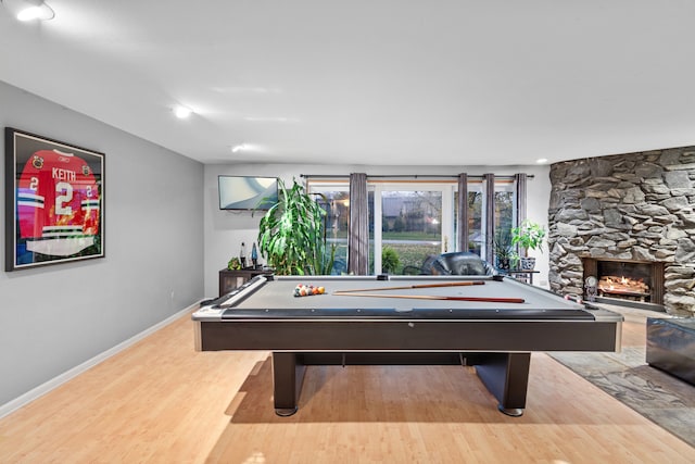 game room featuring a stone fireplace, billiards, and hardwood / wood-style flooring