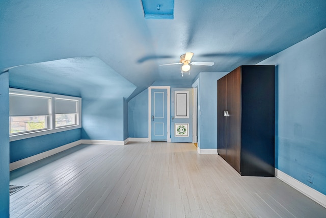 bonus room featuring a textured ceiling, light wood-type flooring, ceiling fan, and lofted ceiling