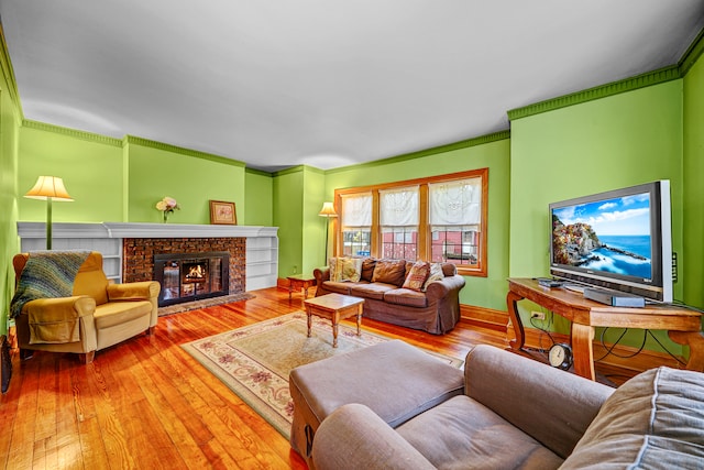 living room featuring ornamental molding, wood-type flooring, and a brick fireplace