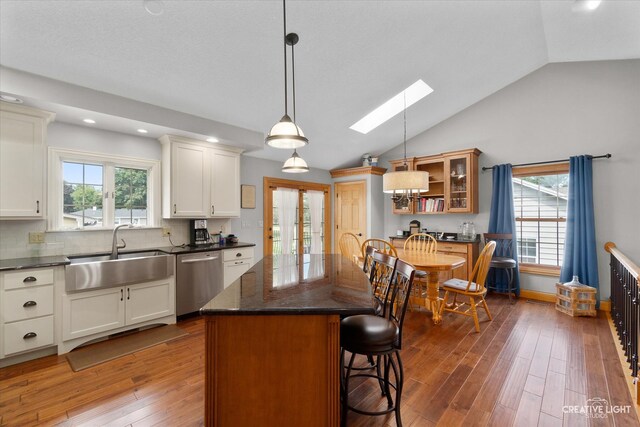 kitchen featuring hardwood / wood-style floors, sink, a skylight, stainless steel dishwasher, and a kitchen island