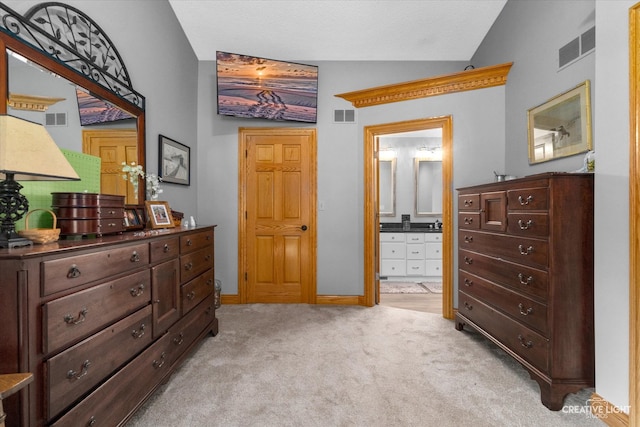 bedroom featuring light colored carpet, lofted ceiling, and connected bathroom