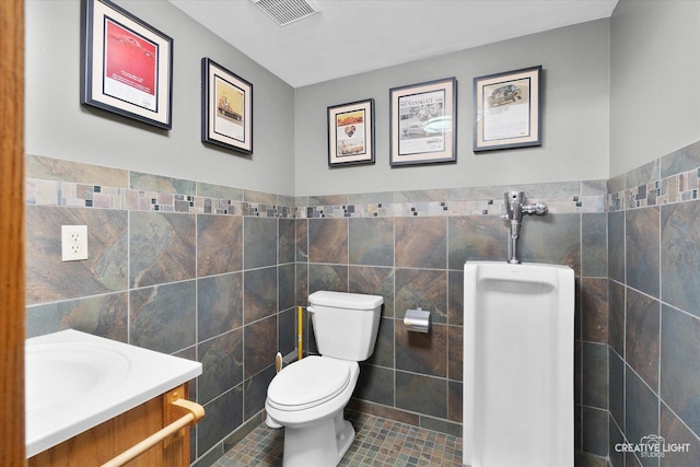 bathroom featuring toilet, vanity, tile patterned floors, and tile walls