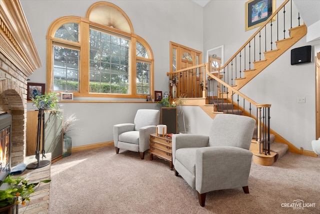 sitting room featuring carpet, a towering ceiling, and a fireplace