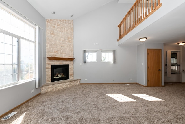 unfurnished living room featuring carpet, a fireplace, and a high ceiling