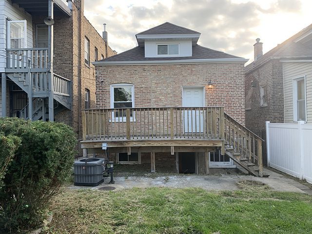 rear view of house with central air condition unit, a lawn, and a deck