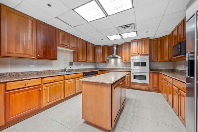 kitchen featuring stainless steel appliances, wall chimney exhaust hood, a paneled ceiling, stone counters, and a kitchen island