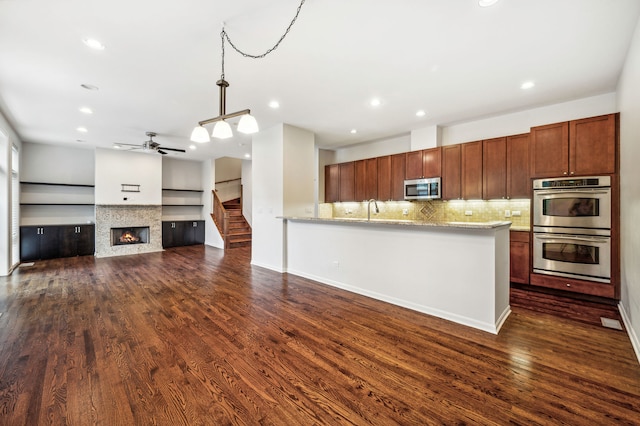 kitchen featuring stainless steel appliances, light stone counters, and dark hardwood / wood-style flooring