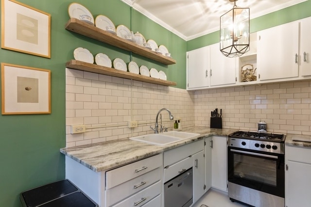 kitchen with decorative backsplash, appliances with stainless steel finishes, sink, pendant lighting, and white cabinetry