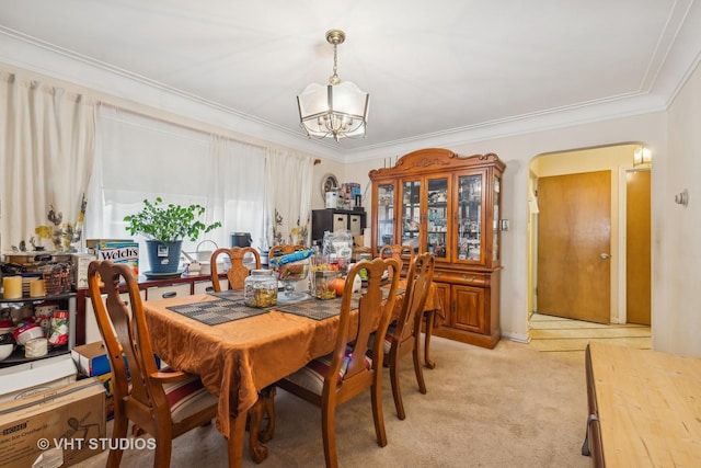 dining room featuring crown molding, light colored carpet, and a notable chandelier