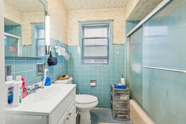 full bathroom with vanity, toilet, enclosed tub / shower combo, and tile walls