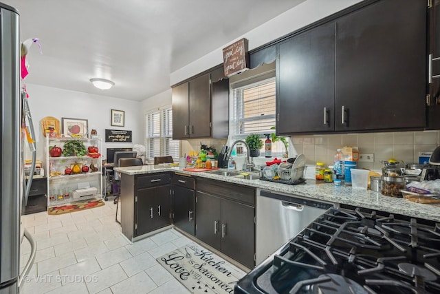 kitchen with kitchen peninsula, stainless steel appliances, light stone counters, and sink