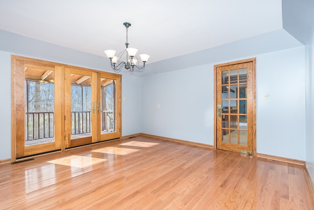 unfurnished room with a chandelier, french doors, and light wood-type flooring