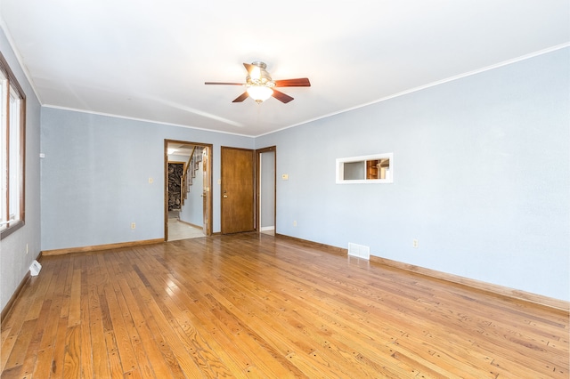 empty room featuring ceiling fan, a healthy amount of sunlight, light wood-type flooring, and ornamental molding