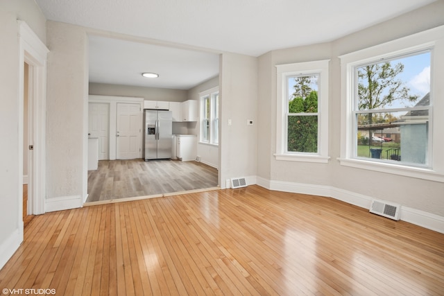 unfurnished living room with light wood-type flooring and a wealth of natural light