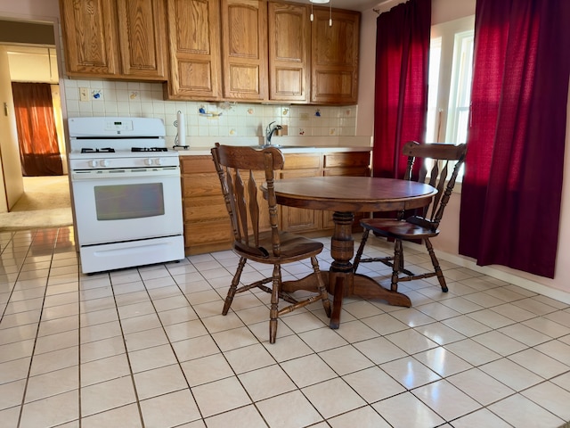 kitchen featuring white gas range, light tile patterned floors, and tasteful backsplash