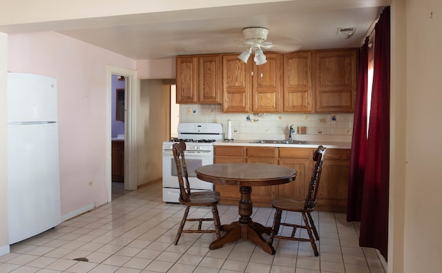 kitchen featuring decorative backsplash, light tile patterned floors, sink, ceiling fan, and white appliances