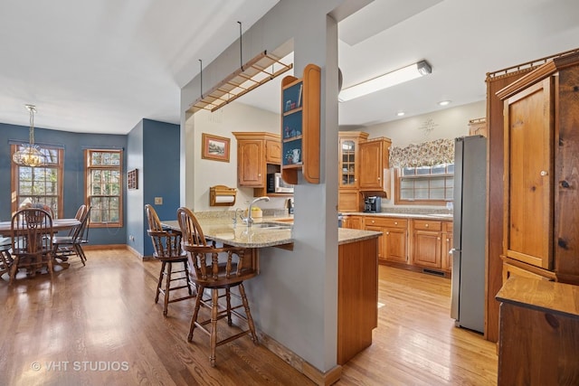 2418 Bennington Ln, Mchenry, IL 60050 - kitchen with stainless steel appliances, a sink, a kitchen bar, a peninsula, and light wood finished floors