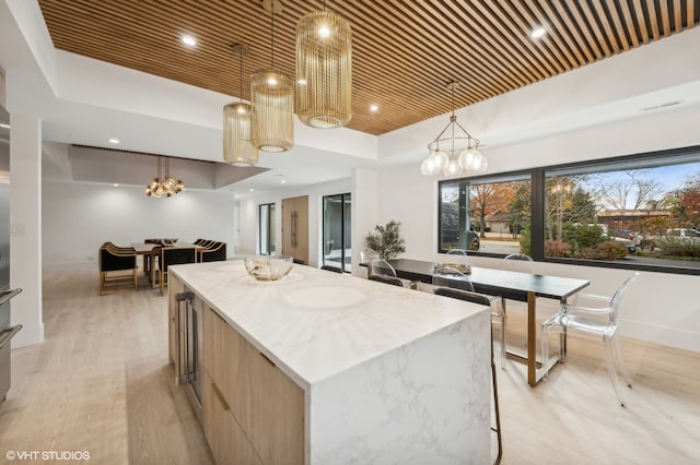 kitchen with wooden ceiling, hanging light fixtures, light brown cabinetry, a kitchen island, and light wood-type flooring