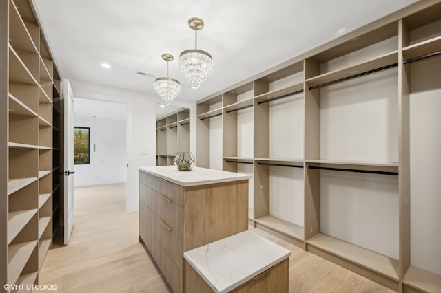 walk in closet featuring light hardwood / wood-style floors and an inviting chandelier